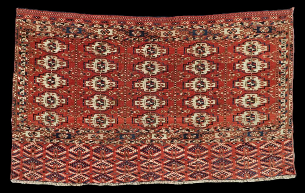 An antique hand-woven Tekke Turkmen chuval face featuring a grid of twenty-five repeating guls in deep red, navy blue, and ivory wool.