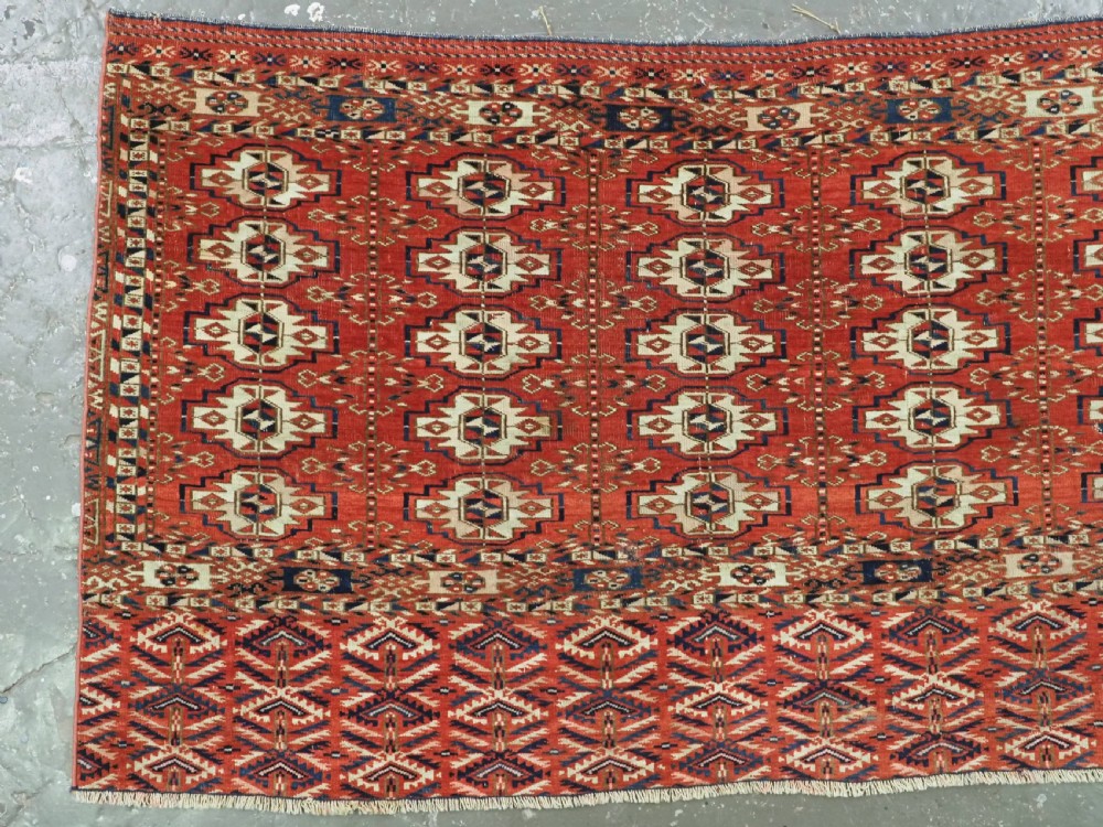 An antique hand-woven Tekke Turkmen chuval face featuring a grid of twenty-five repeating guls in deep red, navy blue, and ivory wool. View II