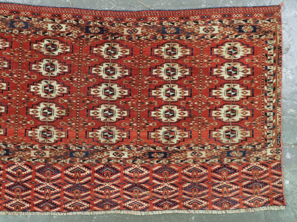 An antique hand-woven Tekke Turkmen chuval face featuring a grid of twenty-five repeating guls in deep red, navy blue, and ivory wool. View III
