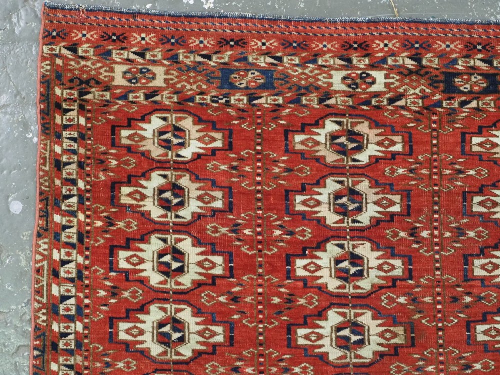 An antique hand-woven Tekke Turkmen chuval face featuring a grid of twenty-five repeating guls in deep red, navy blue, and ivory wool. View IV
