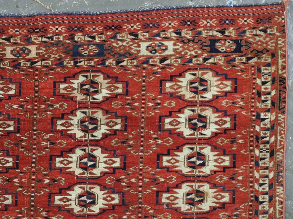 An antique hand-woven Tekke Turkmen chuval face featuring a grid of twenty-five repeating guls in deep red, navy blue, and ivory wool. View VI