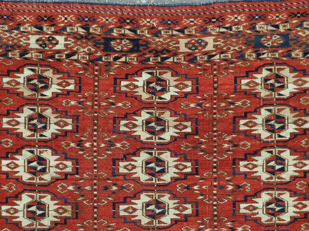 An antique hand-woven Tekke Turkmen chuval face featuring a grid of twenty-five repeating guls in deep red, navy blue, and ivory wool. View VIII