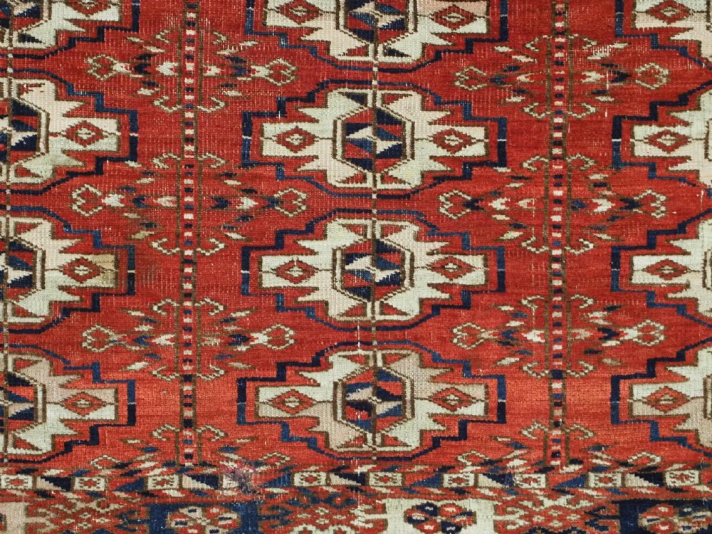 An antique hand-woven Tekke Turkmen chuval face featuring a grid of twenty-five repeating guls in deep red, navy blue, and ivory wool. View IX