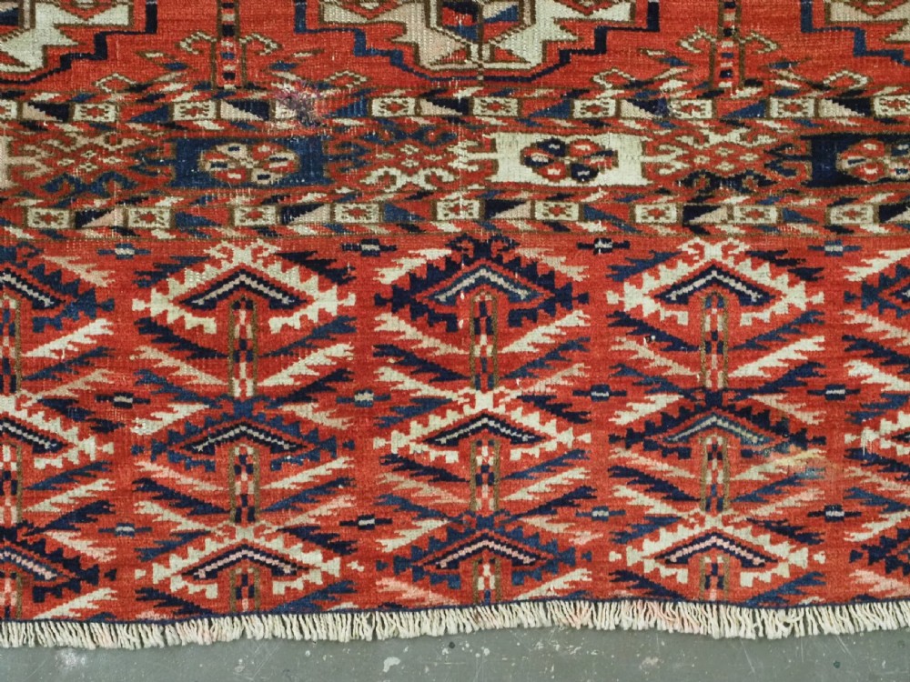 An antique hand-woven Tekke Turkmen chuval face featuring a grid of twenty-five repeating guls in deep red, navy blue, and ivory wool. View X
