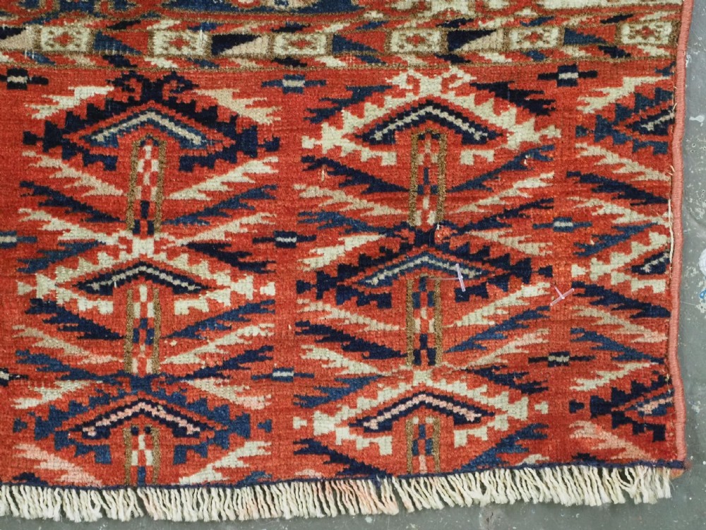 An antique hand-woven Tekke Turkmen chuval face featuring a grid of twenty-five repeating guls in deep red, navy blue, and ivory wool. View XI