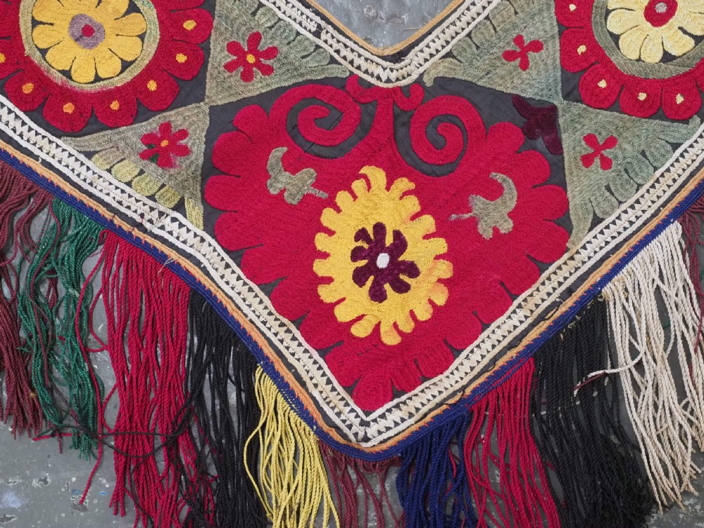 A V-shaped black cloth band decorated with vibrant red and yellow silk embroidered rosettes and finished with multi-coloured yarn fringe. View IV
