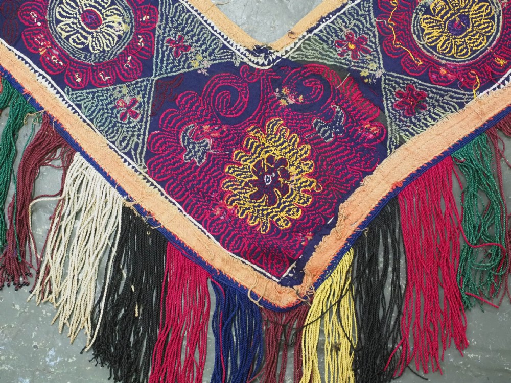 A V-shaped black cloth band decorated with vibrant red and yellow silk embroidered rosettes and finished with multi-coloured yarn fringe. View VIII
