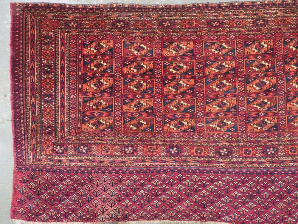 A rectangular late 19th-century Tekke Turkmen chuval face woven in madder red and navy wool featuring repeated geometric Aina gul motifs above a detailed floral elem skirt. View IV