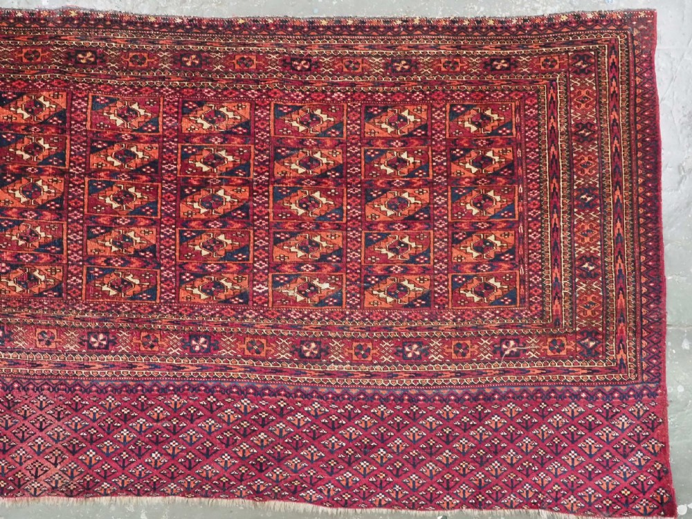 A rectangular late 19th-century Tekke Turkmen chuval face woven in madder red and navy wool featuring repeated geometric Aina gul motifs above a detailed floral elem skirt. View V
