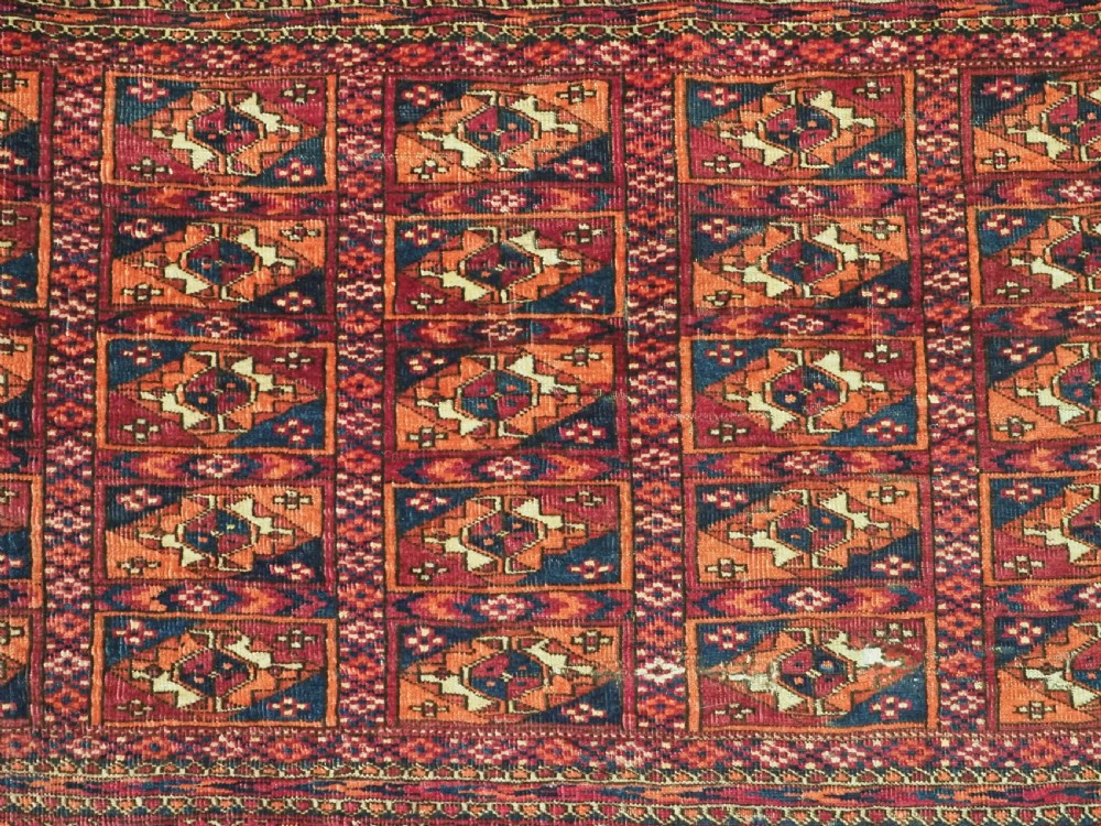 A rectangular late 19th-century Tekke Turkmen chuval face woven in madder red and navy wool featuring repeated geometric Aina gul motifs above a detailed floral elem skirt. View VI