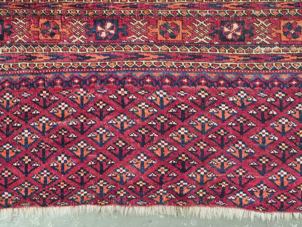 A rectangular late 19th-century Tekke Turkmen chuval face woven in madder red and navy wool featuring repeated geometric Aina gul motifs above a detailed floral elem skirt. View VII