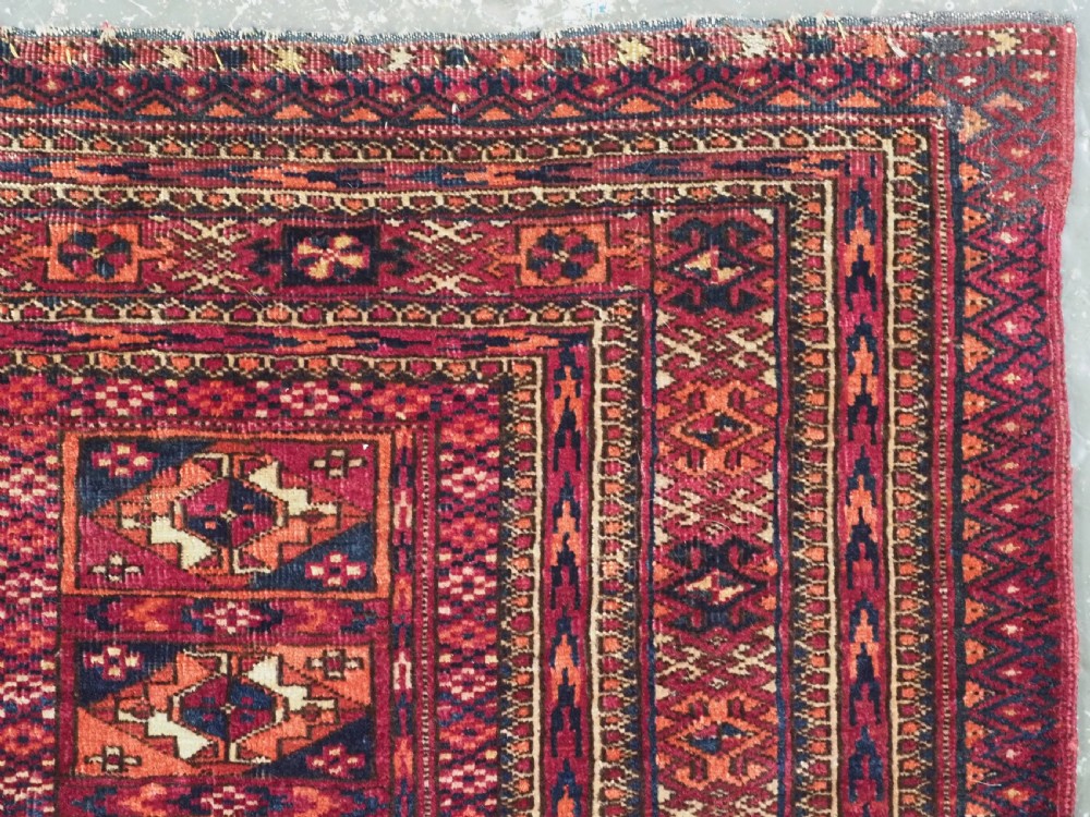A rectangular late 19th-century Tekke Turkmen chuval face woven in madder red and navy wool featuring repeated geometric Aina gul motifs above a detailed floral elem skirt. View IX