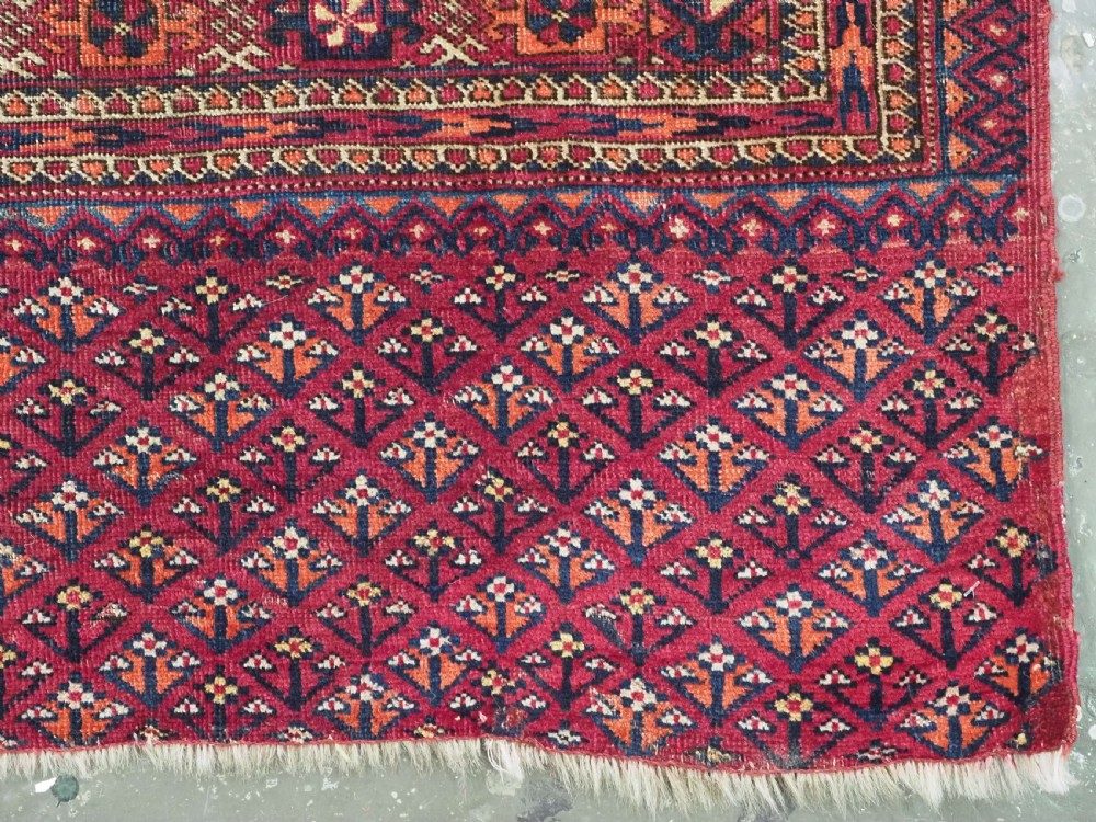 A rectangular late 19th-century Tekke Turkmen chuval face woven in madder red and navy wool featuring repeated geometric Aina gul motifs above a detailed floral elem skirt. View X
