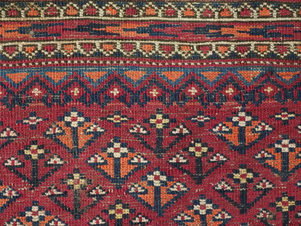 A rectangular late 19th-century Tekke Turkmen chuval face woven in madder red and navy wool featuring repeated geometric Aina gul motifs above a detailed floral elem skirt. View XI