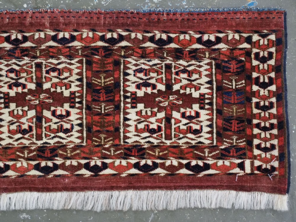 A horizontal handwoven Tekke Turkmen wool textile featuring three rectangular panels with tree designs bordered by intricate geometric patterns in red, navy, and ivory. View III