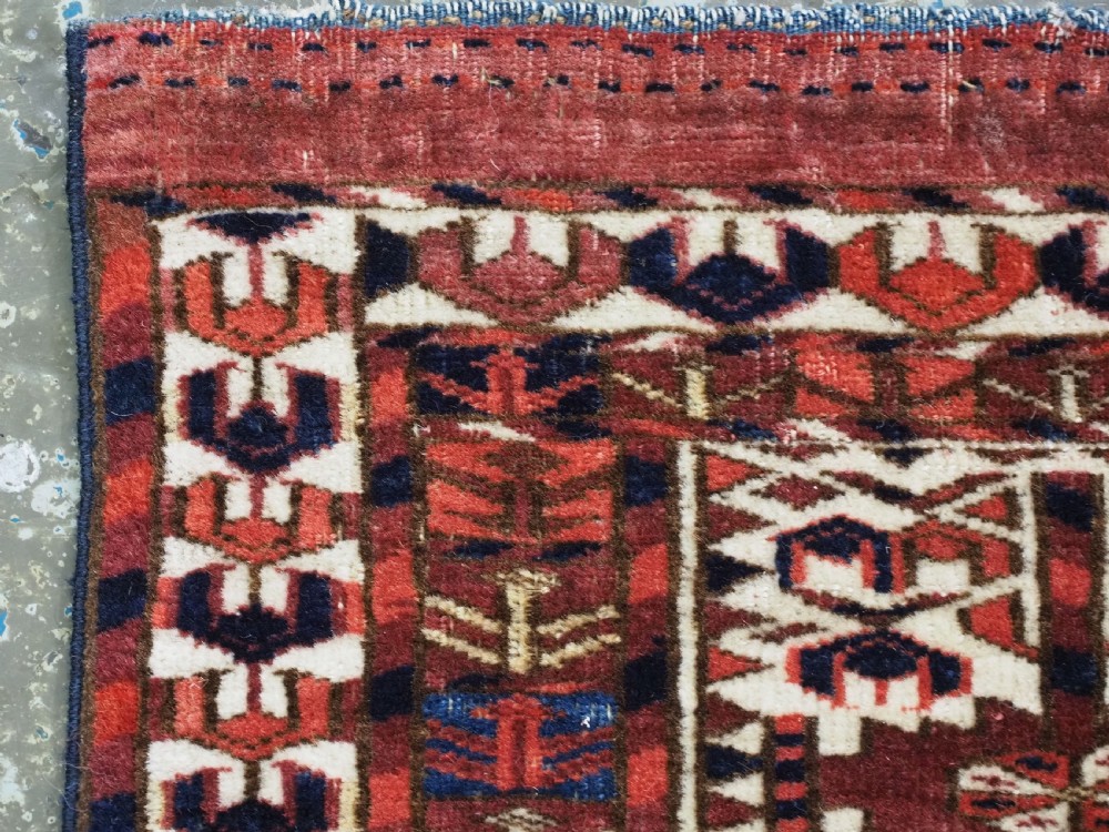 A horizontal handwoven Tekke Turkmen wool textile featuring three rectangular panels with tree designs bordered by intricate geometric patterns in red, navy, and ivory. View V