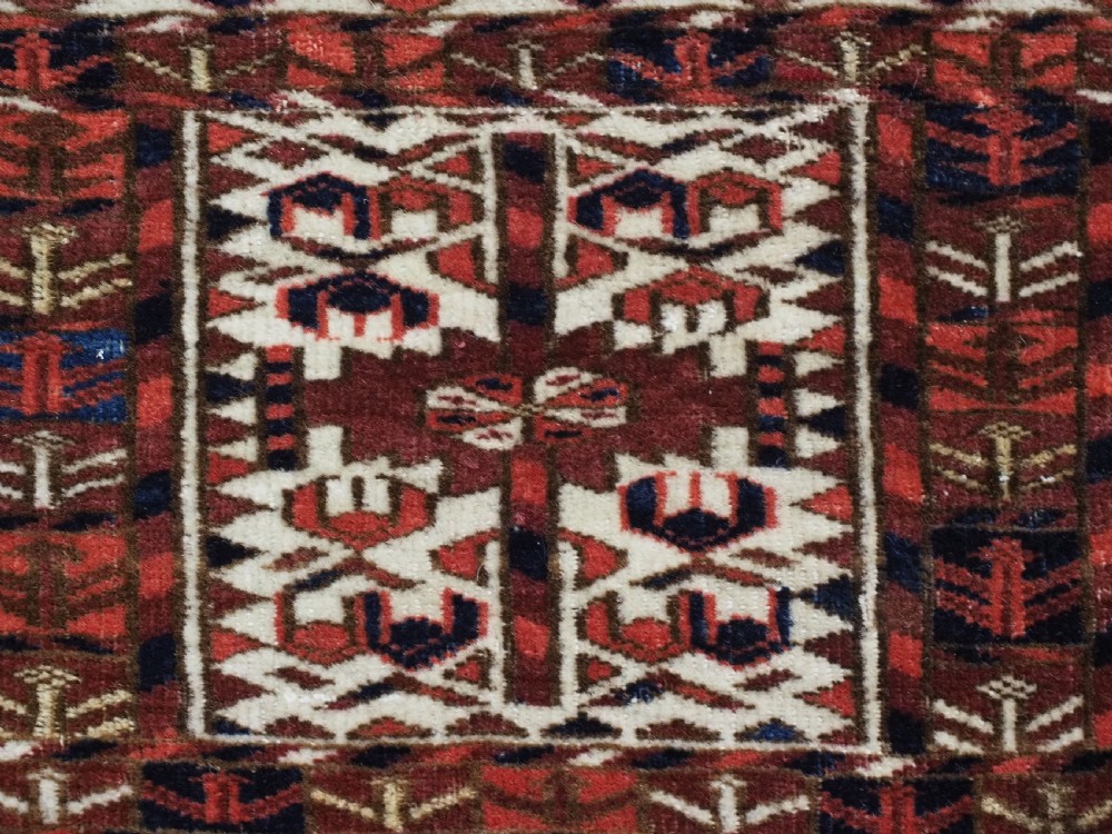 A horizontal handwoven Tekke Turkmen wool textile featuring three rectangular panels with tree designs bordered by intricate geometric patterns in red, navy, and ivory. View VI