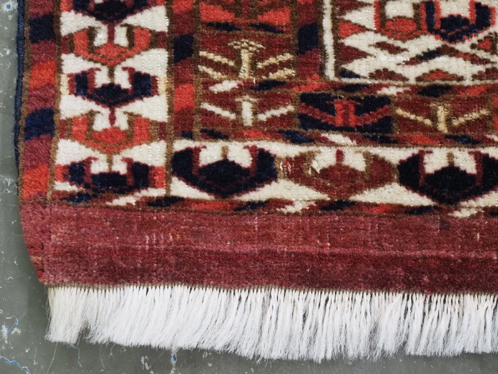A horizontal handwoven Tekke Turkmen wool textile featuring three rectangular panels with tree designs bordered by intricate geometric patterns in red, navy, and ivory. View VII