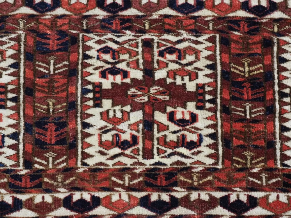 A horizontal handwoven Tekke Turkmen wool textile featuring three rectangular panels with tree designs bordered by intricate geometric patterns in red, navy, and ivory. View VIII