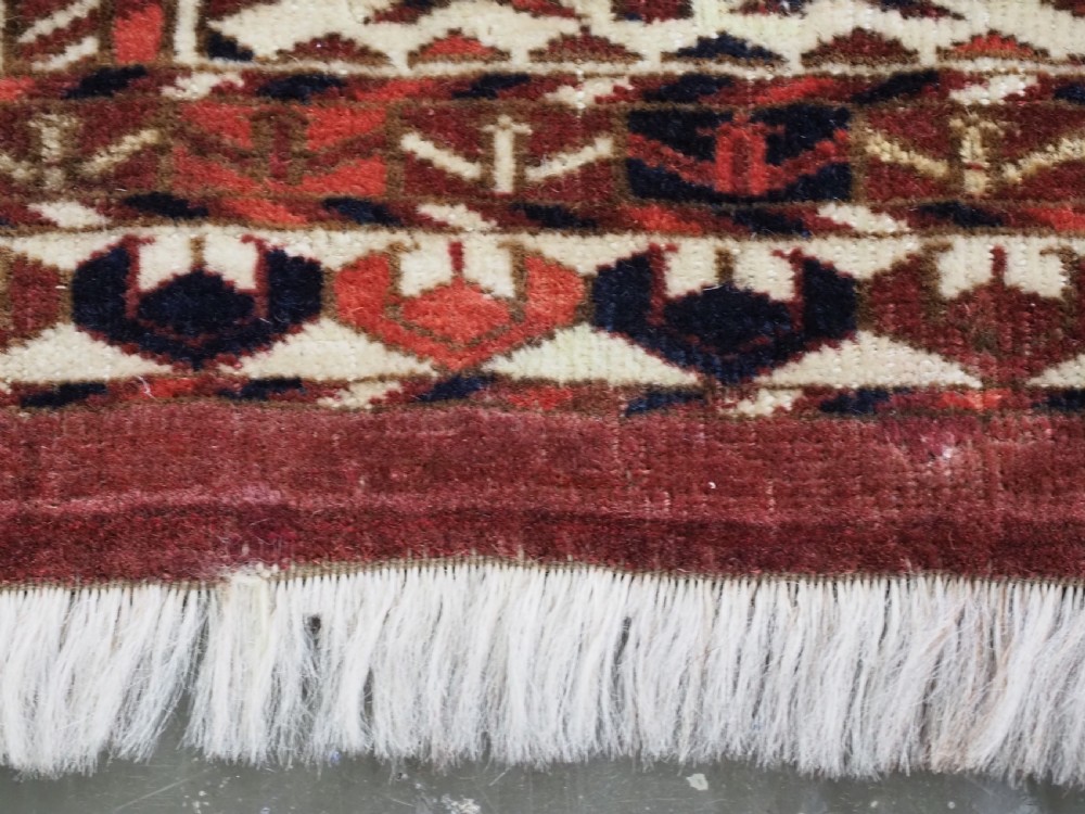 A horizontal handwoven Tekke Turkmen wool textile featuring three rectangular panels with tree designs bordered by intricate geometric patterns in red, navy, and ivory. View IX