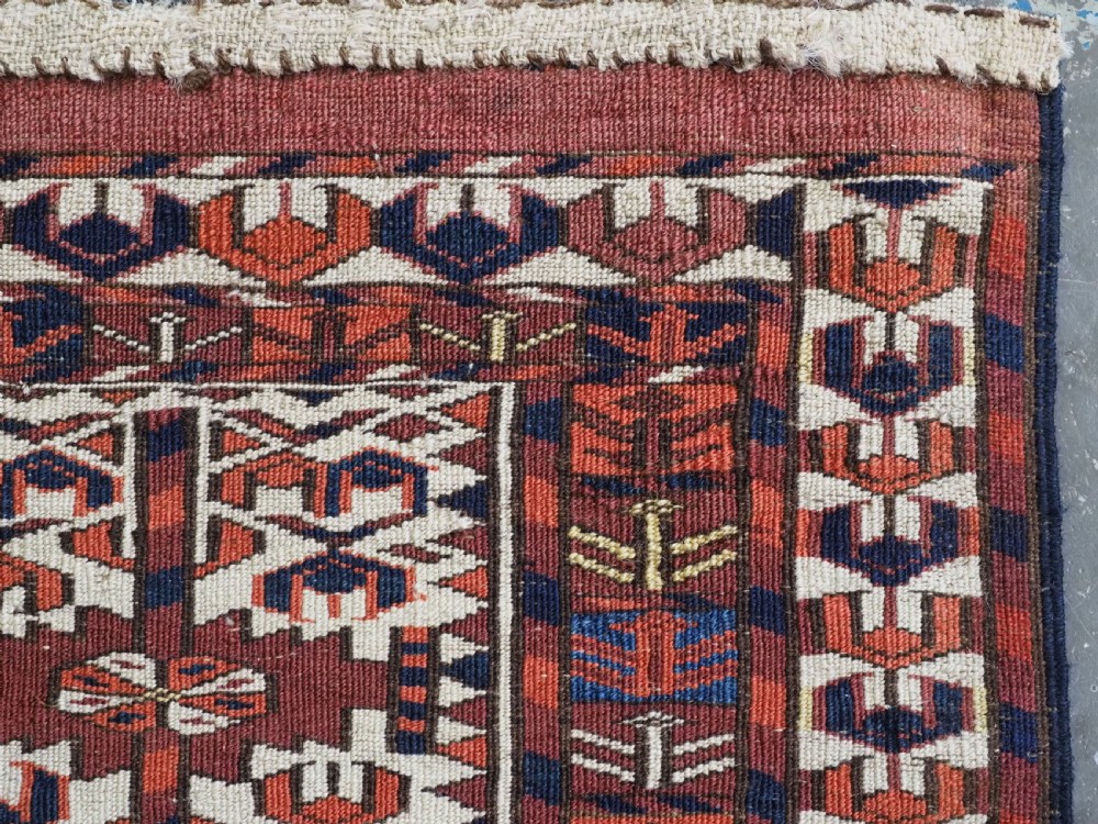 A horizontal handwoven Tekke Turkmen wool textile featuring three rectangular panels with tree designs bordered by intricate geometric patterns in red, navy, and ivory. View XII