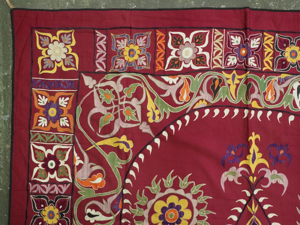 An antique rectangular Uzbek suzani featuring silk floral needlework embroidery on a deep red cotton ground with a pointed arch motif and floral borders. View VI