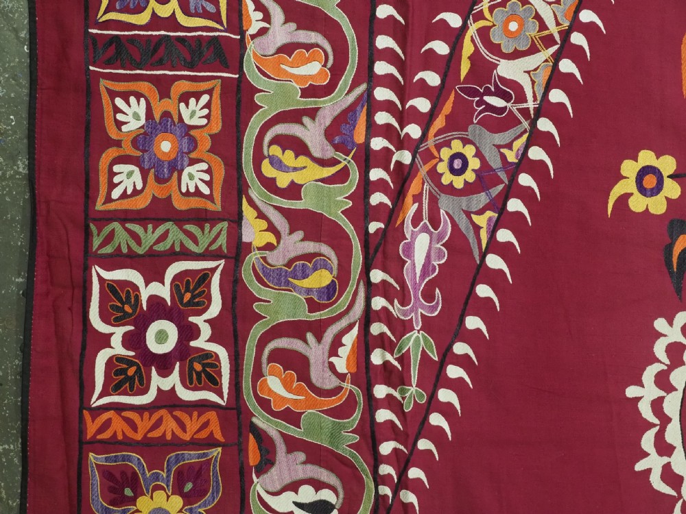 An antique rectangular Uzbek suzani featuring silk floral needlework embroidery on a deep red cotton ground with a pointed arch motif and floral borders. View VII