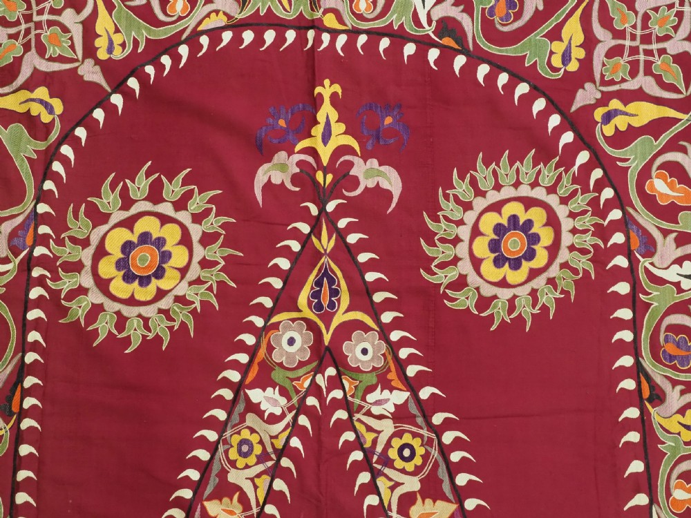 An antique rectangular Uzbek suzani featuring silk floral needlework embroidery on a deep red cotton ground with a pointed arch motif and floral borders. View VIII