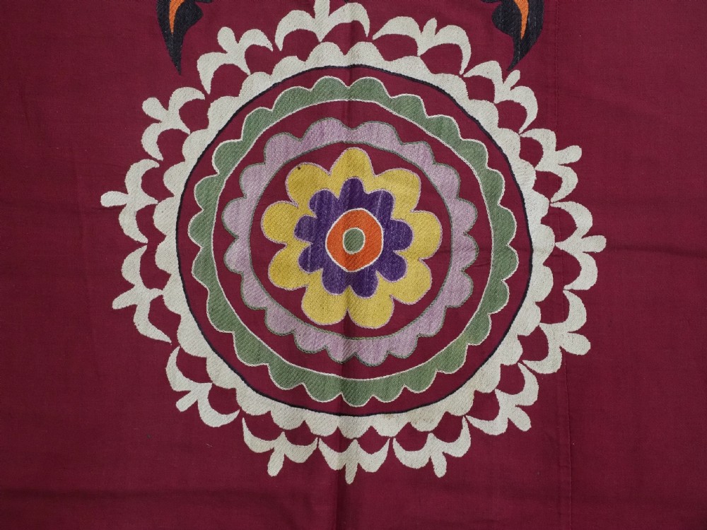An antique rectangular Uzbek suzani featuring silk floral needlework embroidery on a deep red cotton ground with a pointed arch motif and floral borders. View X