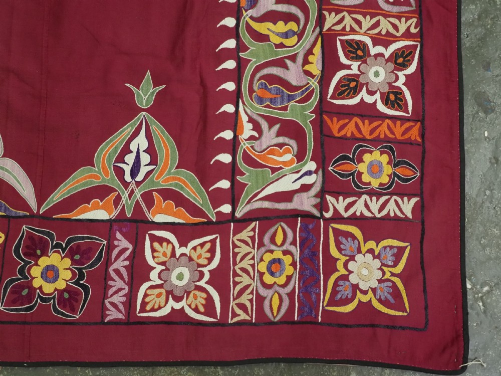 An antique rectangular Uzbek suzani featuring silk floral needlework embroidery on a deep red cotton ground with a pointed arch motif and floral borders. View XII