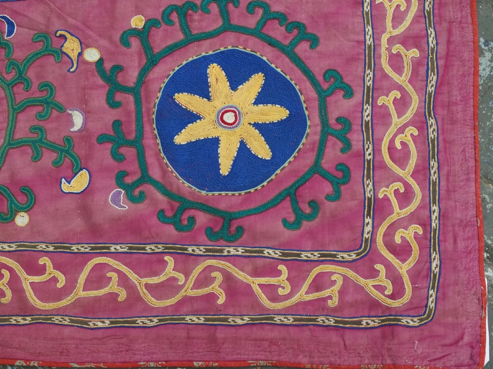 A rectangular hand-embroidered pink silk on cotton suzani textile featuring circular floral motifs, star shapes, and scrolling vine borders. View X