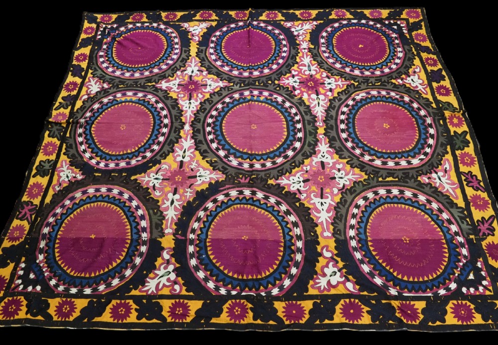 An antique Uzbek Samarkand suzani textile displaying nine large purple circular medallions framed by a yellow floral border.