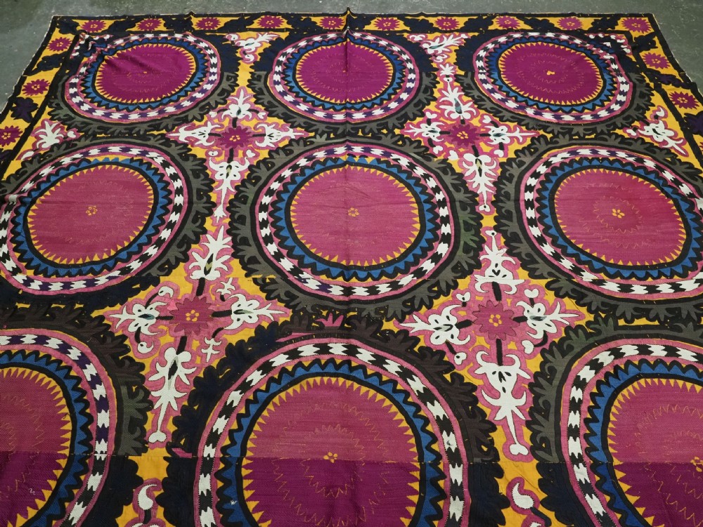 An antique Uzbek Samarkand suzani textile displaying nine large purple circular medallions framed by a yellow floral border. View II