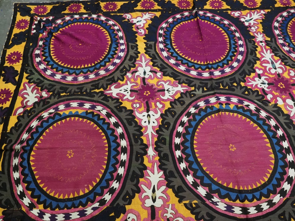 An antique Uzbek Samarkand suzani textile displaying nine large purple circular medallions framed by a yellow floral border. View IV