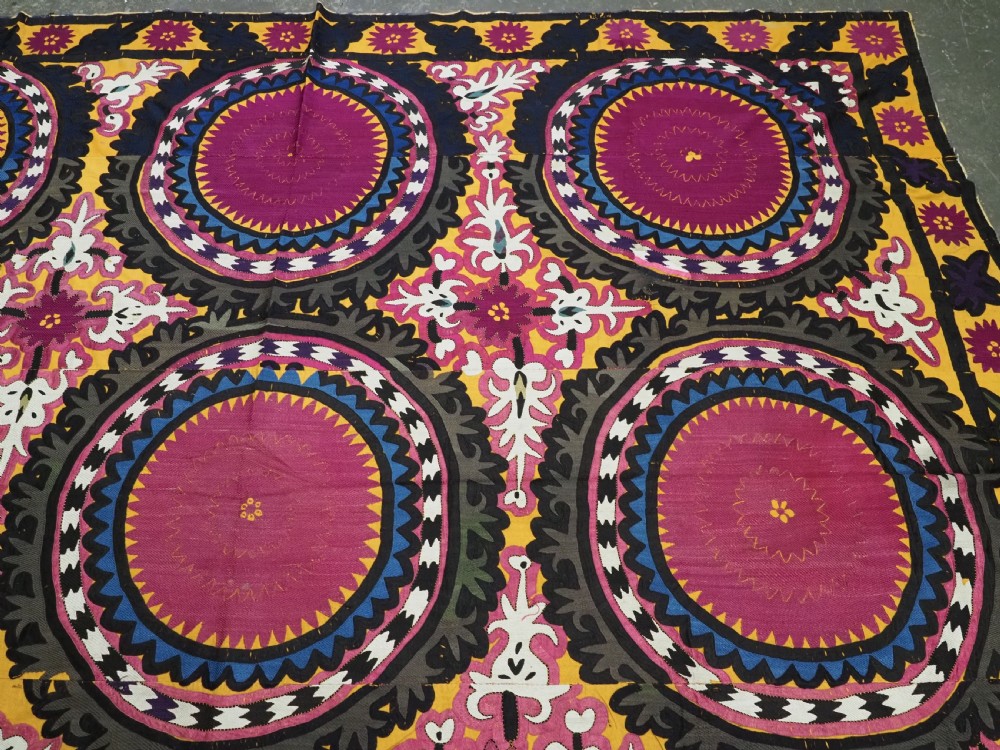 An antique Uzbek Samarkand suzani textile displaying nine large purple circular medallions framed by a yellow floral border. View V