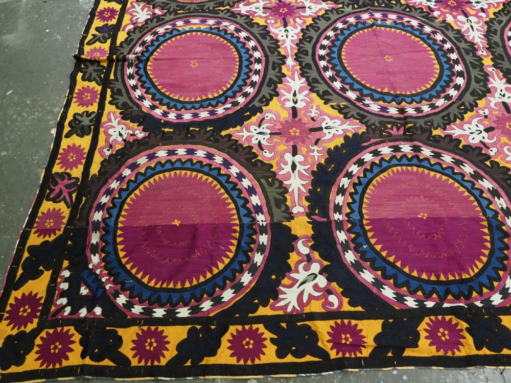An antique Uzbek Samarkand suzani textile displaying nine large purple circular medallions framed by a yellow floral border. View VI