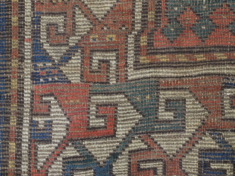 An antique Caucasian Kazak long rug featuring central geometric medallions in red, navy blue, and green with detailed border patterns. View XV