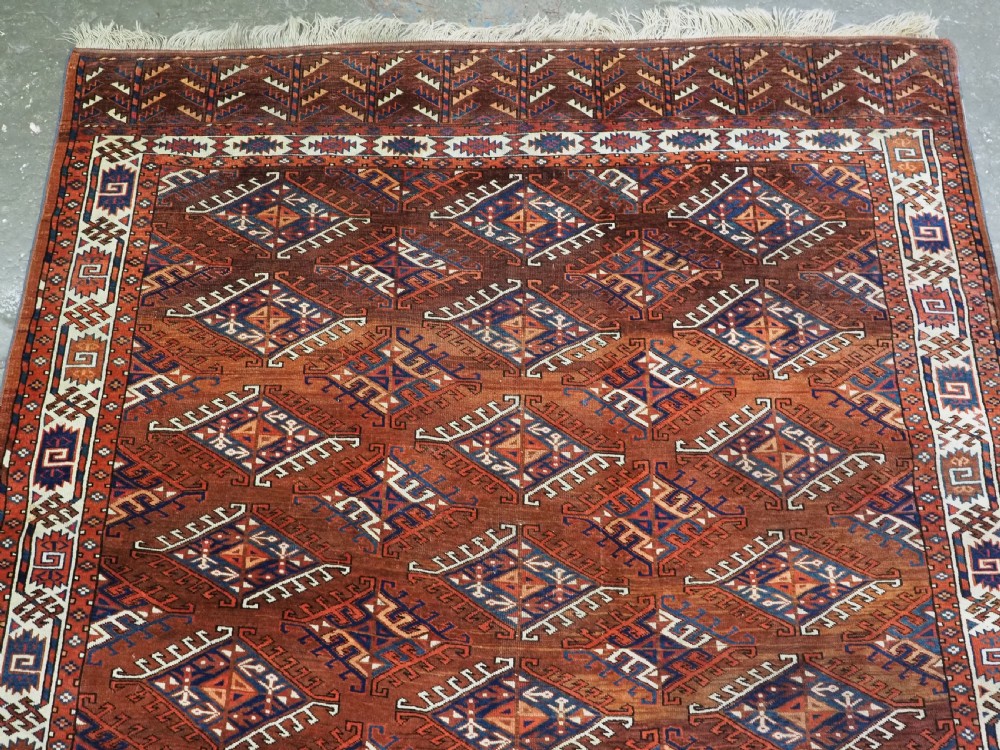 An antique Turkmen hand-knotted wool carpet featuring a repeating diamond dyrnak gul motif on a deep terracotta field with geometric borders. View III