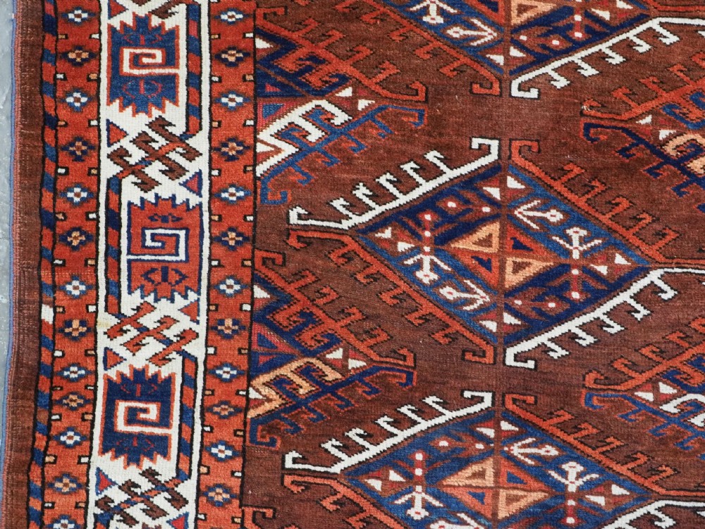 An antique Turkmen hand-knotted wool carpet featuring a repeating diamond dyrnak gul motif on a deep terracotta field with geometric borders. View VII