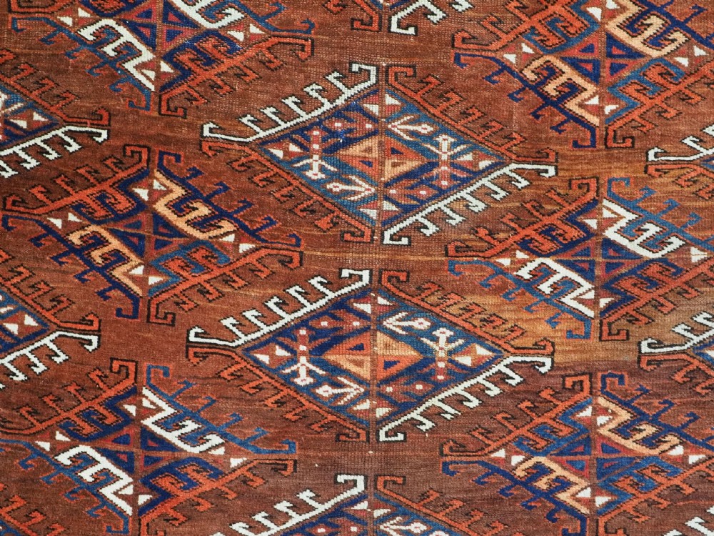 An antique Turkmen hand-knotted wool carpet featuring a repeating diamond dyrnak gul motif on a deep terracotta field with geometric borders. View IX