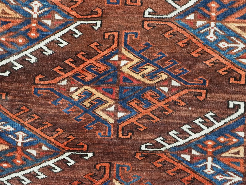 An antique Turkmen hand-knotted wool carpet featuring a repeating diamond dyrnak gul motif on a deep terracotta field with geometric borders. View XI