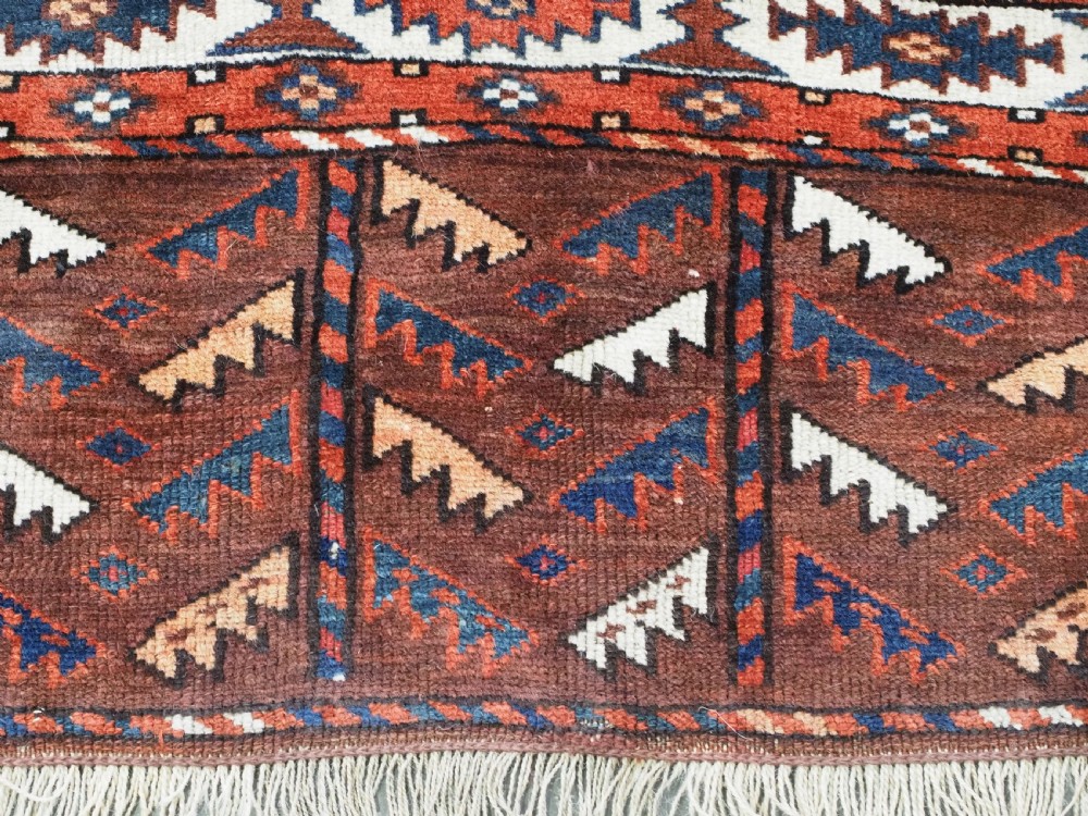 An antique Turkmen hand-knotted wool carpet featuring a repeating diamond dyrnak gul motif on a deep terracotta field with geometric borders. View XIII