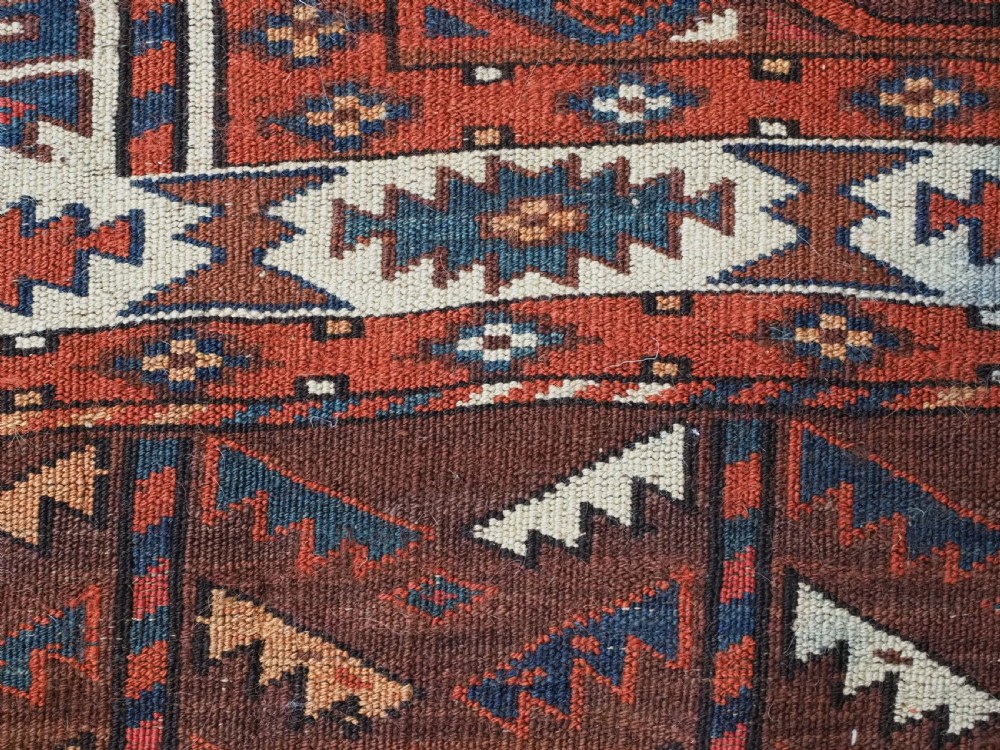 An antique Turkmen hand-knotted wool carpet featuring a repeating diamond dyrnak gul motif on a deep terracotta field with geometric borders. View XIV