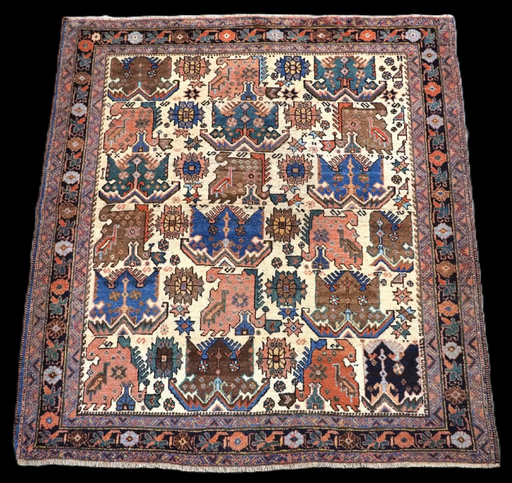 An antique hand-knotted Afshar wool rug featuring stylised dragon and phoenix motifs in blue, terracotta, and brown over an ivory ground within a geometric patterned border.