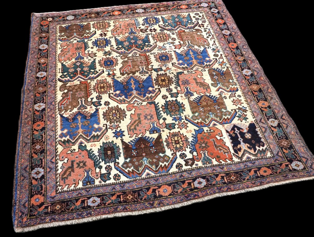 An antique hand-knotted Afshar wool rug featuring stylised dragon and phoenix motifs in blue, terracotta, and brown over an ivory ground within a geometric patterned border. View II