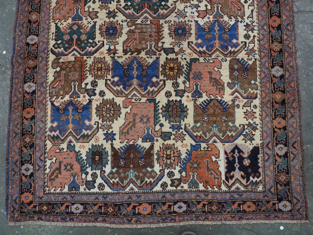 An antique hand-knotted Afshar wool rug featuring stylised dragon and phoenix motifs in blue, terracotta, and brown over an ivory ground within a geometric patterned border. View IV