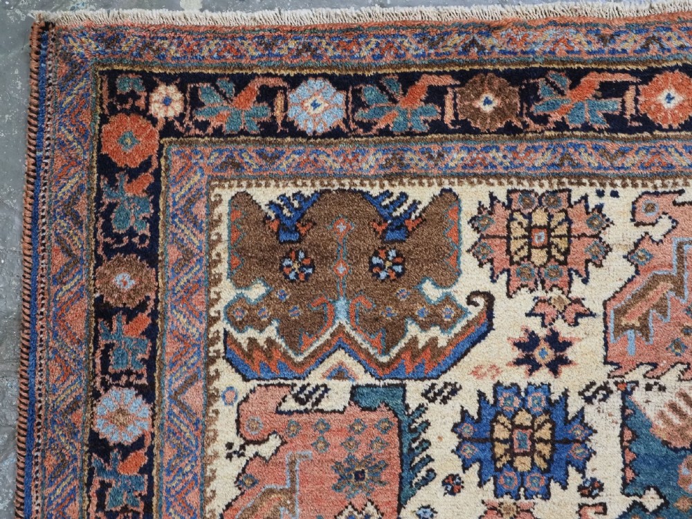 An antique hand-knotted Afshar wool rug featuring stylised dragon and phoenix motifs in blue, terracotta, and brown over an ivory ground within a geometric patterned border. View V