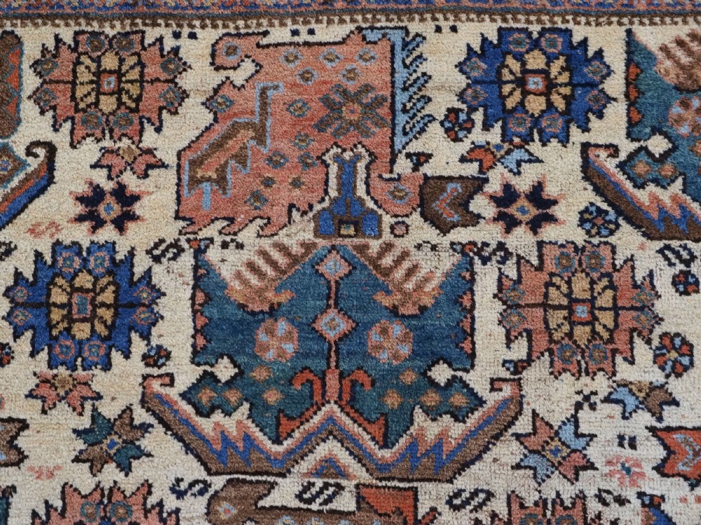 An antique hand-knotted Afshar wool rug featuring stylised dragon and phoenix motifs in blue, terracotta, and brown over an ivory ground within a geometric patterned border. View VII
