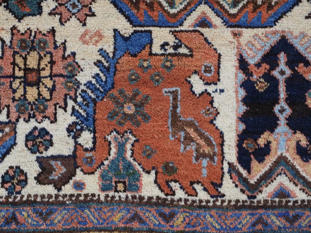 An antique hand-knotted Afshar wool rug featuring stylised dragon and phoenix motifs in blue, terracotta, and brown over an ivory ground within a geometric patterned border. View XI