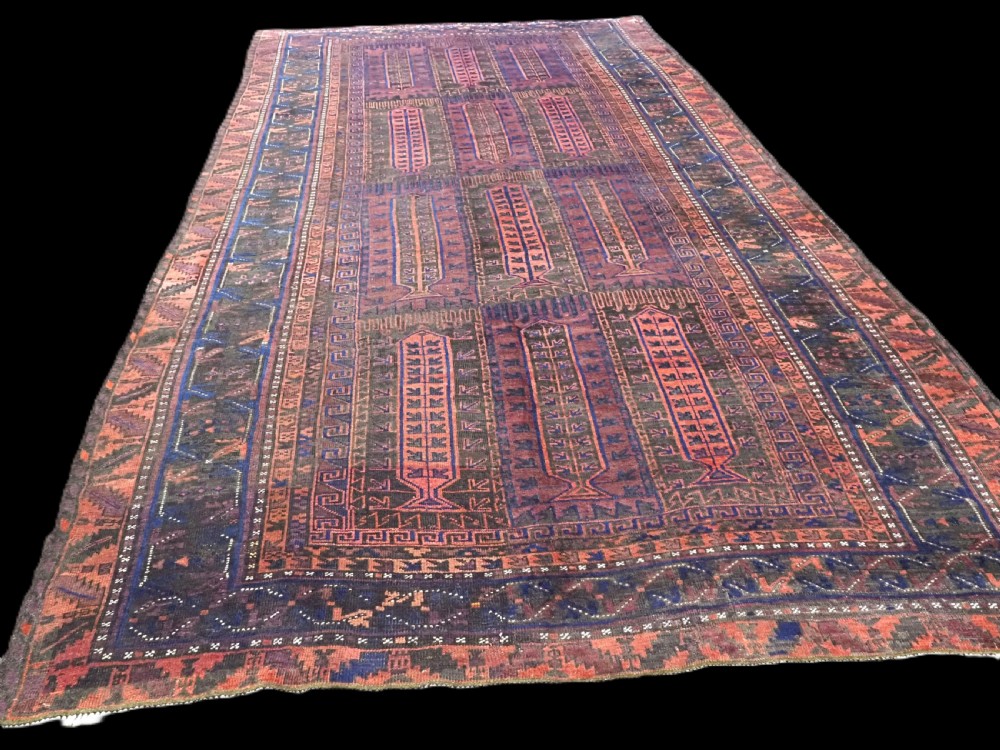 A late nineteenth-century hand-knotted wool Baluch carpet featuring repeated geometric column motifs in indigo, dark red, and purple shades within multiple patterned borders. View II